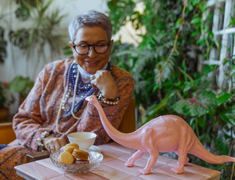 Photo of Eldelry Woman Looking at a Dinosour Miniature
